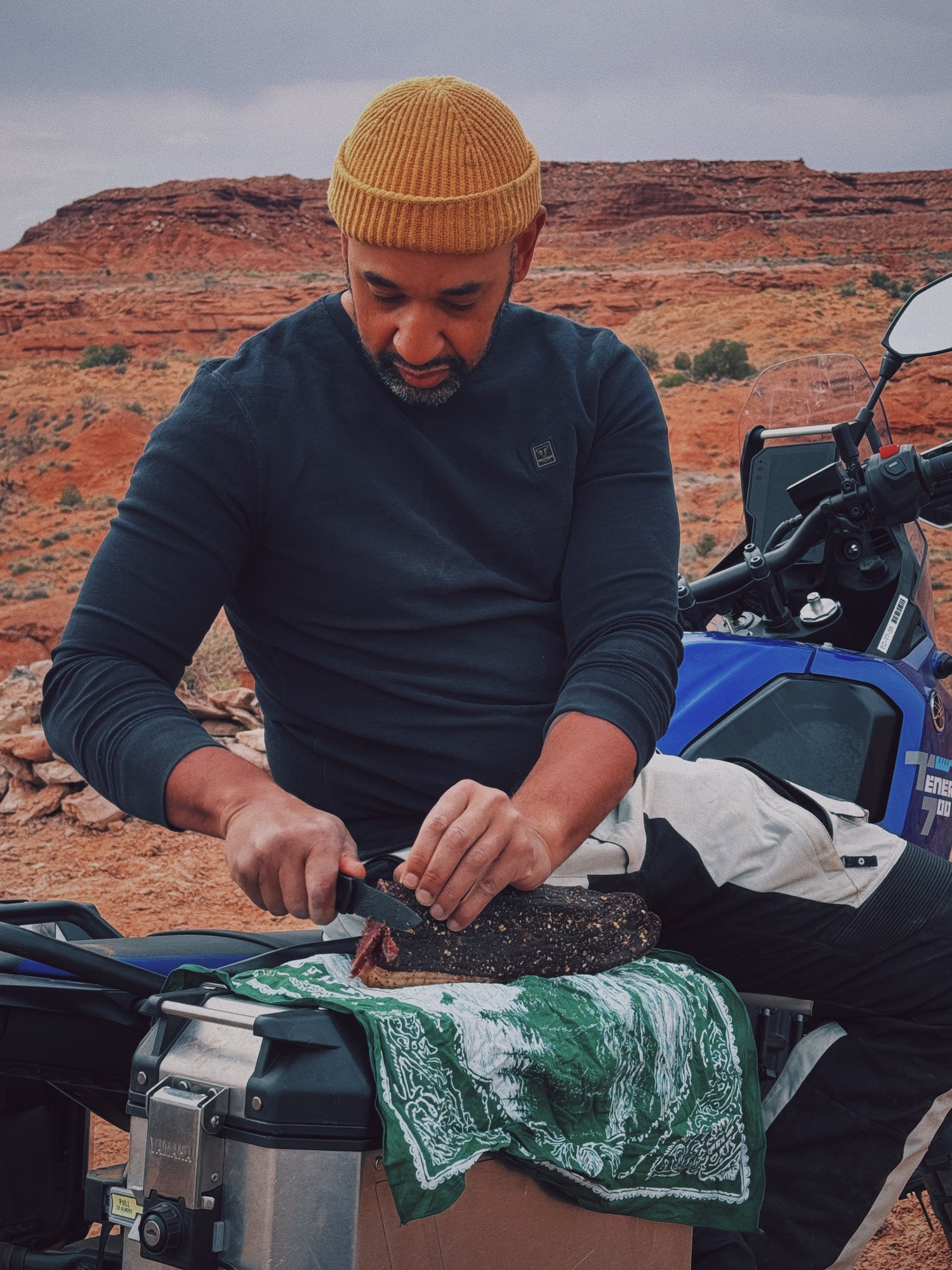 Man preparing a whole grass-fed slab of Brave Biltong in a desert landscape