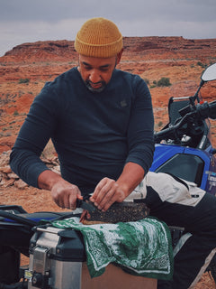 Man preparing a whole grass-fed slab of Brave Biltong in a desert landscape